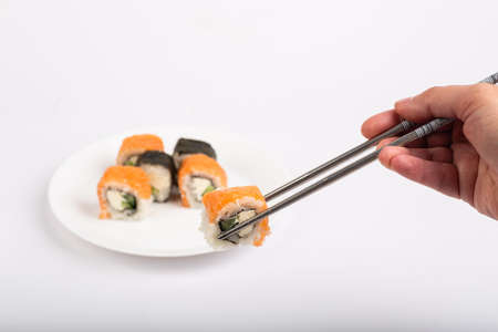 Roll of sushi on a plate, Sushi roll on a tablet, white background, Sushi roll and hand with...