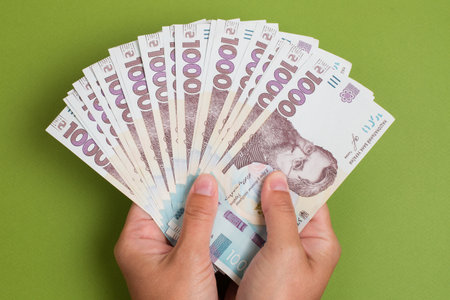 Stack of new ukrainian hryvnia banknotes in hands on green background. Hryvnia 1000 uahの写真素材