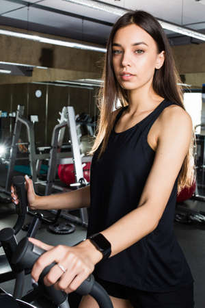 Young beautiful woman performs exercise in modern gym on racetrackの写真素材