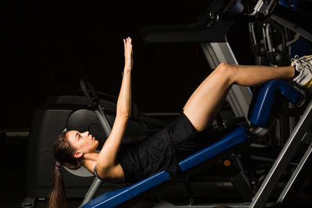 Young beautiful woman performs exercise in modern gym clubの写真素材