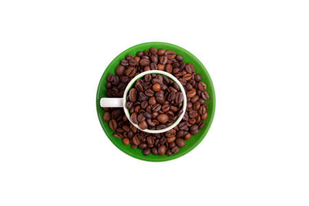 Ceramic cup on a green saucer filled with coffee beans, top viewの写真素材