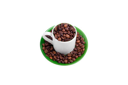 Ceramic cup on a green saucer filled with coffee beans, top viewの写真素材