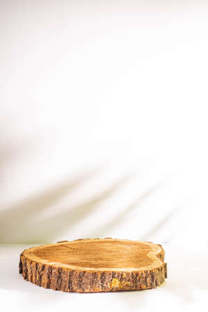 Wooden podium for product presentation on white background with shadow of palm leafの写真素材