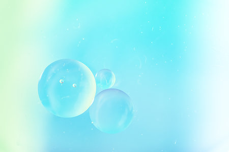 Gradient background in white and sky soft tones. Macro drops of oil on the surface of the water....