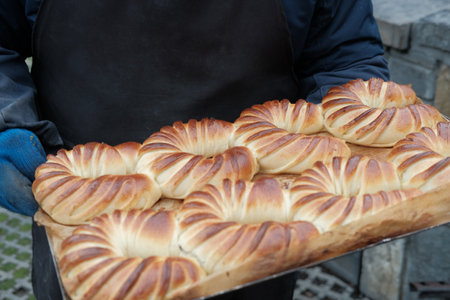Freshly baked buns on a tray in the hands of a faceless man. Small family bakery. concept of local...