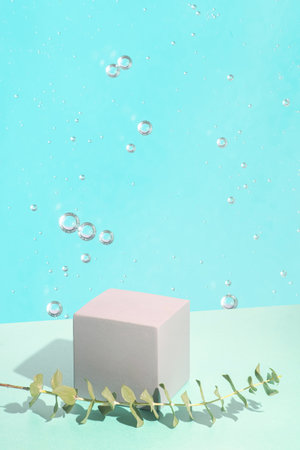 cement cubic podium and a sprig of eucalyptus on a blue dewy background. Mockup for the demonstration of cosmetic products.の写真素材