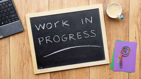 Work in progress written on a chalkboard at the officeの写真素材