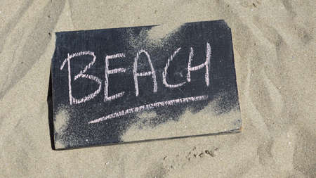 Beach written on a chalkboard in the sunny sandの写真素材
