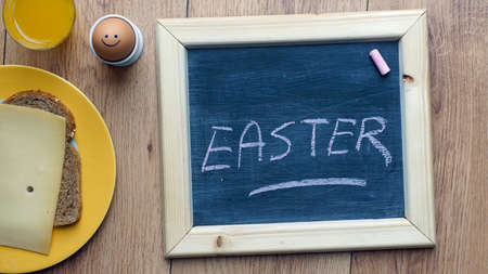 Easter written on a chalkboard on a breakfast tableの写真素材