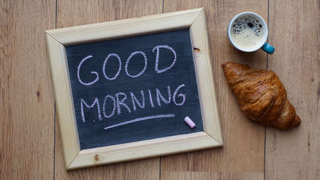 Gooed morning written on a chalkboard next to a croissant and coffeeの写真素材
