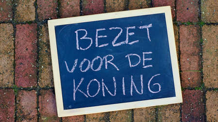 Occupy fot the king written in Dutch on a chalkboard that is located on the sidewalk for King's dayの写真素材
