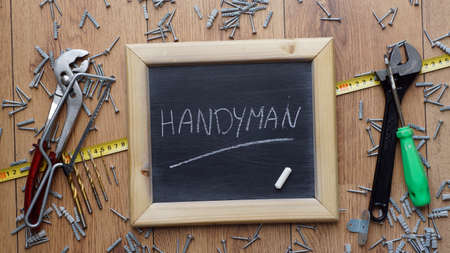 Handyman written on a chalkboard next to tools, screws and dowelsの写真素材