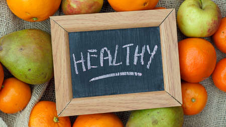 Healthy written on a chalkboard beween fruitの写真素材