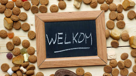 Welcome in Dutch written on a chalkboard between ginger nuts and candy's for the Dutch Santa-Claus celebration of the 5th of Decemberの写真素材