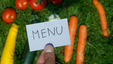 Menu written on a card in front of vegatables              の写真素材