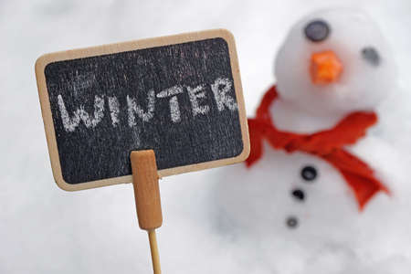 Winter written on a card with a snowman behind                          の写真素材