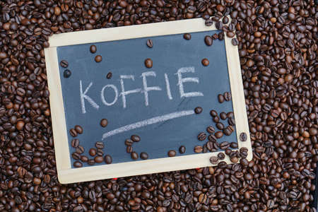 Coffee written in Dutch on a chalkboard between beans             の写真素材