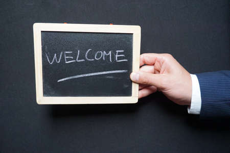 Welcome written on a board holding in a hand by a businessman                            の写真素材