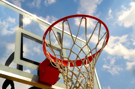 Bottom view of a basketball hoop with the backboard and sky in the background.の写真素材