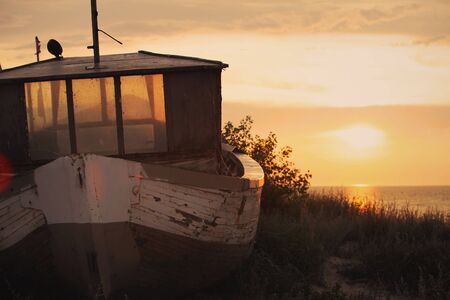 Old boat on sand dunes at sunset.の写真素材