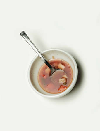 Half eaten vegetable soup in white bowl on white background.の写真素材