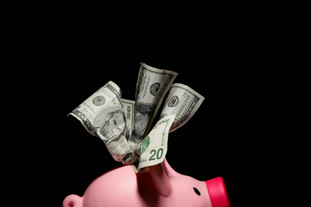 Crumpled money and piggy bank on black background with copy space.の写真素材