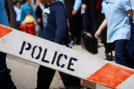 Police barricade with children in the background. Focus on the Police barricade.の写真素材