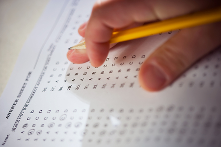 Multiple choice test and hand with pencil.