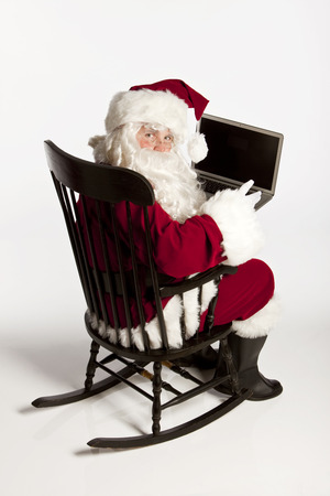 Santa in his rocking chair with his laptop.の写真素材