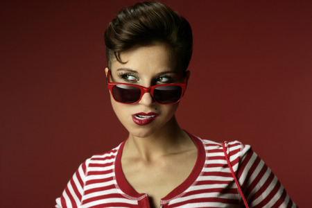 Brunette in red striped shirt with red background.の写真素材
