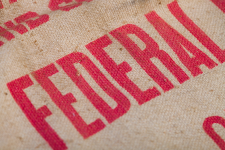 Detail of the word federal on an antique canvas bag.
