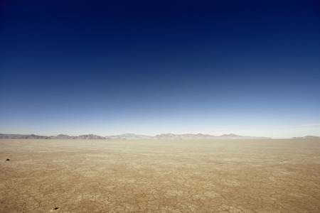 Flat desert scene with mountains at the horizon.