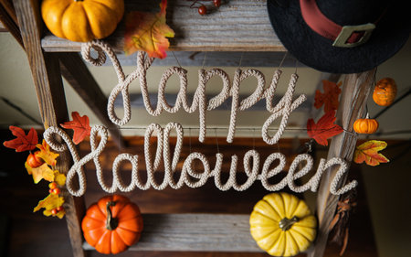 overhead view of hanging "Happy Halloween" text hanging from wooden ladder with autumn decorの素材