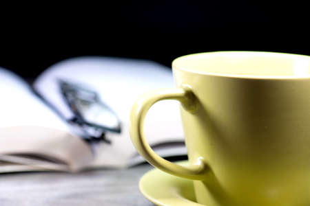 Coffee cup, reading glasses and a bookの写真素材