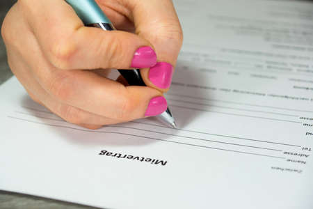 feminine hand signing a contract for an apartment