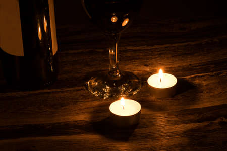 Two candles and a glass of wineの写真素材