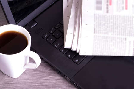 A cup of coffee, laptop and a newspaperの写真素材