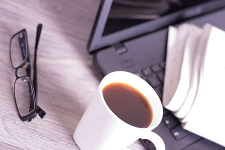A cup of coffee, computer and a newspaper