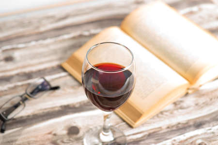 A book, reading glasses and a glass of red wineの写真素材