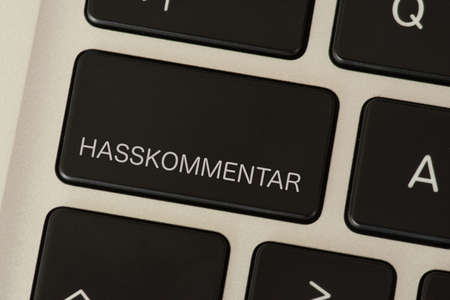 A computer and a button with the hate comment print