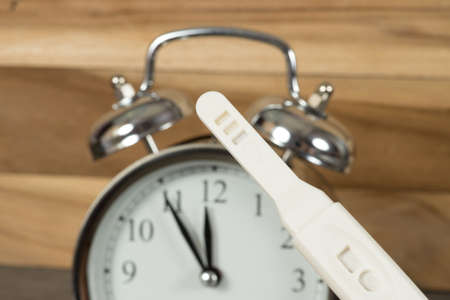 An alarm clock as a biological clock and a pregnancy test or ovulation testの写真素材