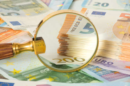 A magnifying glass and many euro billsの写真素材