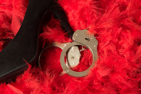 High heels and handcuffs on a base of red feathersの写真素材