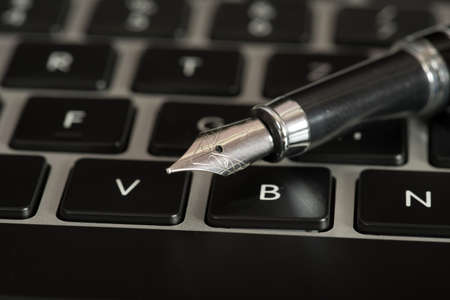 A computer and a fountain penの写真素材