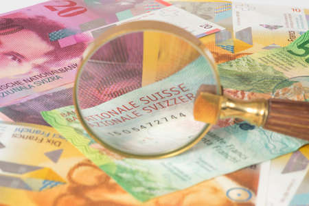 Swiss franc and a magnifying glassの写真素材