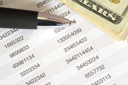 Dollar bills, spreadsheet and a pen