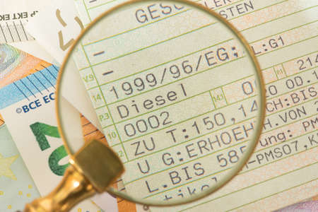 A vehicle license for a diesel car, a magnifying glass and euro bills
