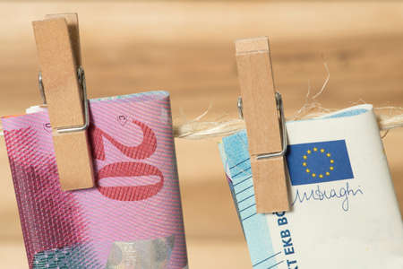 Swiss franc and euro banknote on a clothesline with clothespin
