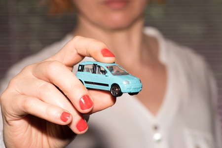 A woman is holding a car in her handの写真素材