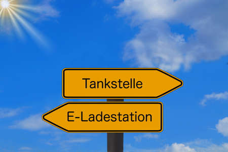 Two signs point to a gas station and charging station for electric carsの写真素材